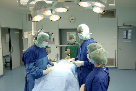 Abbildung von 4 Personen und einem Patient in einem modernen Operationssaal