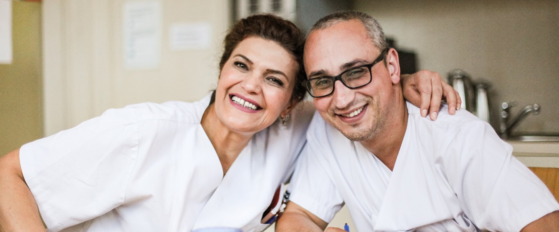 Zwei glückliche medizinische Angestellte liegen sich im Arm