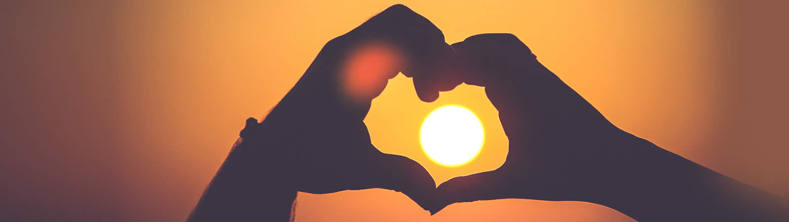Abbildung: Palliativ - Hände formen Herz im Sonnenuntergang